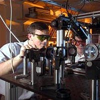 Georgia Tech Physicists Alex Kuzmich (left) and Dzmitry Matsukevich operate optical equipment used to transfer information from two different groups of atoms onto a single photon. 
Georgia Tech Photo: Gary Meek 
