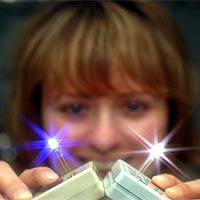 LAUREN ROHWER displays the two solid-state light-emitting devices using quantum dots her team has developed. One is blue and the other is white. (Photo by Randy Montoya)