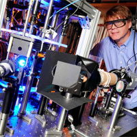 <p>
	Michael Chapman, a professor in the School of Physics at Georgia Tech, poses with optical equipment in his laboratory. Chapman’s research team is exploring squeezed states using atoms of Bose-Einstein condensates. (Click image for high-resolution version. Credit: Gary Meek)</p>
