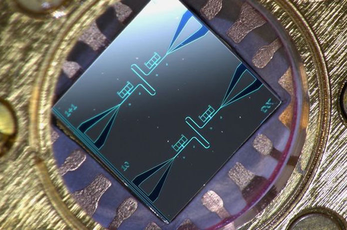 <p>Photo of a centimeter-sized silicon chip, which has two parallel superconducting resonators and quantum-circuit refrigerators connected to them. Image: Kuan Yen Tan.</p>
